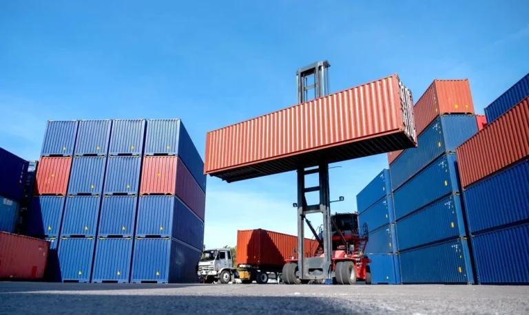 Forklift stacking shipping container in freight yard surrounded by cargo units during transloading operations at Phoenix Warehouse facility