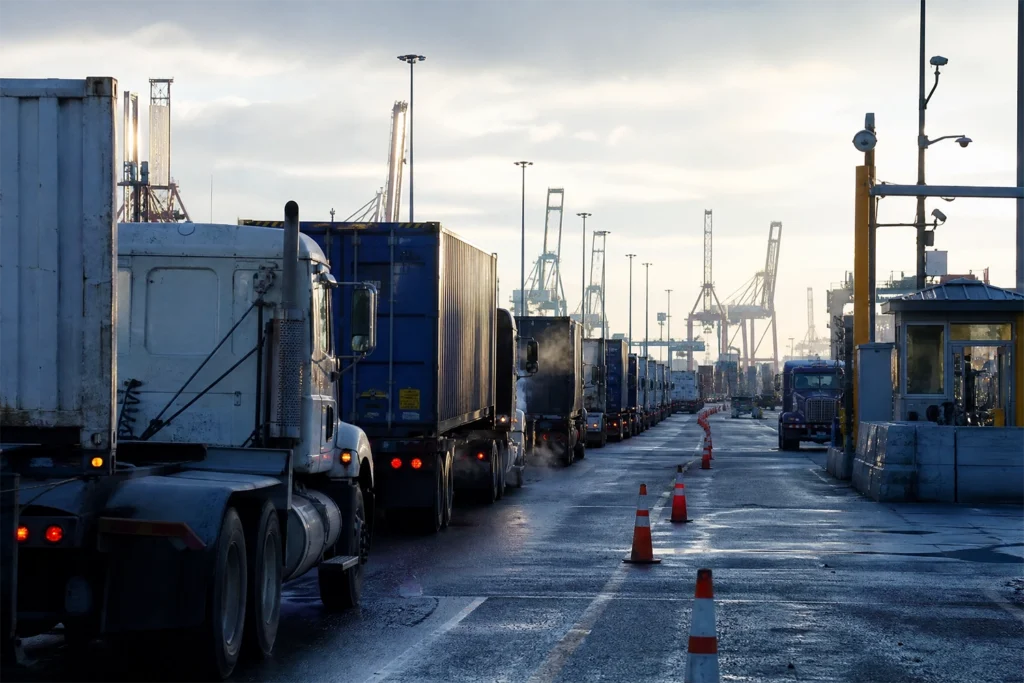 Long line of semi-trucks with containers waiting at Port Newark terminal gate during morning port congestion